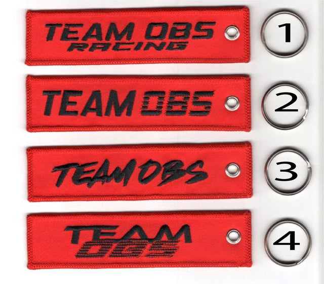 Team OBS flight tag keychains in red with embroidered logos and metal keyrings