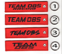 Team OBS flight tag keychains in red with embroidered logos and metal keyrings